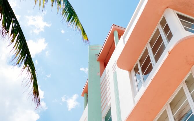peach/pastel green tone beach house with palm tree leaves, with beautiful blue skies